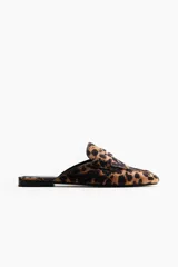 Mules estilo mocasín con punta redonda, modelo penny con costura tradicional en el empeine, forro interior negro y exterior con estampado animal print de leopardo.