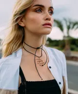 Collar con cordón de cuero negro y dije plateado con forma de coral con incrustaciones de piedras celestes.