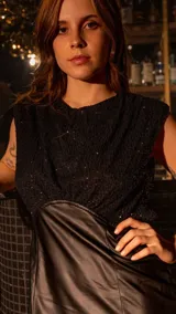 Vestido corto negro con top de lentejuelas y falda de cuero sintético.