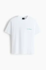 Remera blanca de corte holgado, con cuello redondo y diseño de manga corta. Cuenta con un pequeño estampado tipográfico en color verde en el pecho.
