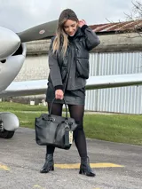 Bolso negro tipo tote de cuero con correa de hombro, hebilla decorativa y etiqueta colgante con la inscripción "NADIA".