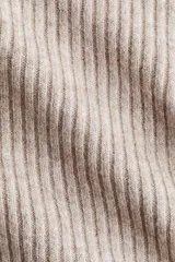 Buzo de punto acanalado suave color beige, con escote off-the-shoulder y corte holgado.