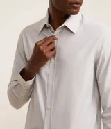 Camisa de vestir masculina de manga larga, confeccionada en tricolina con un sutil estampado de cuadros grid. Presenta cuello clásico, abotonadura frontal y puños con botones.