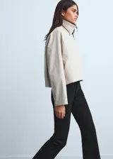 Pantalón de jean negro de tiro medio y corte flare, con diseño crop y bajo deshilachado. Cuenta con cierre de cremallera, botón frontal, trabillas para cinturón y cinco bolsillos clásicos.