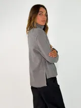 Sweater de punto color azul marino, con cuello alto, manga larga y puños acanalados. Presenta una costura vertical decorativa en el centro del frente y un ruedo acanalado con terminación asimétrica.