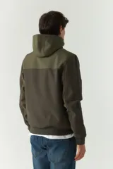 Campera softshell verde con capucha removible, cierre frontal y bolsillos con cierre.