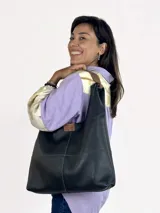 Bolso tote negro de cuero con doble asa al hombro color marrón.
