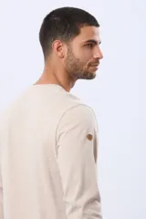 Remera de manga larga en color azul oscuro, con cuello redondo y estampado frontal de paisaje montañoso. Presenta un pequeño parche decorativo en la manga.