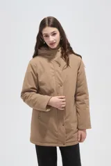 Campera de abrigo color beige, con capucha, cierre frontal con botones a presión y diseño de corte recto y holgado.