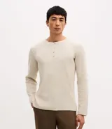 Remera de manga larga estilo Henley, confeccionada en tejido texturizado color beige, con cuello redondo y cierre frontal parcial de botones.