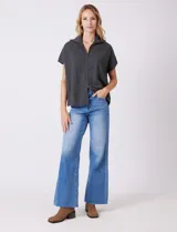 Cardigan gris jaspeado de punto de galga media, con cierre frontal metálico completo y cuello con solapa. Presenta mangas cortas de sisa caída y un corte recto y holgado que llega a la altura de la cadera.