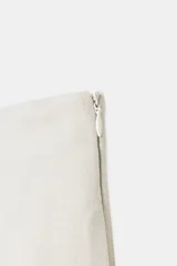 Falda midi de tiro medio, color blanco roto o crema, con pliegues marcados en el delantero y bolsillos laterales ocultos.