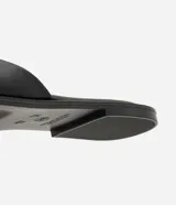 Sandalia mule plana de cuero color negro, con diseño minimalista, capellada ancha y punta cuadrada.