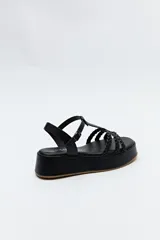 Sandalia de plataforma color marrón con tiras trenzadas y pulsera con hebilla.