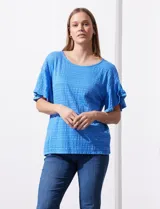 Blusa de mujer color azul vibrante con textura acanalada y pequeños patrones jacquard en relieve. Presenta un escote redondo y mangas cortas con vuelo.