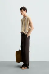 Chaleco de punto crochet con cuello pico y sisa, tejido en bloques de color beige, verde claro, naranja y marrón oscuro.