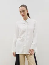 Camisa de corte holgado y diseño clásico, confeccionada en tela satinada con un sutil estampado floral tono sobre tono. Presenta cuello camisero, cierre frontal con botones y mangas largas con puños rectos.