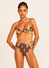 Conjunto de bikini Triya con estampado floral en tonos marrones, naranjas y violetas. El corpiño es strapless con nudo central y la bombacha es de tiro alto con aberturas laterales.
