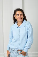 Saco tejido de punto color blanco, con cuello tipo polo, cierre frontal con botones y diseño con flores bordadas en relieve.