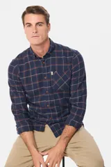 Camisa de viyela a cuadros tipo leñadora, con cuello abotonado, cierre frontal con botones y bolsillo en el pecho.