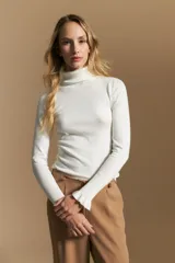 Polera de tejido fino color negro, con cuello alto y mangas largas con terminación sutilmente fruncida. Diseño ajustado al cuerpo.