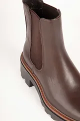 Bota marrón de cuero sintético, estilo Chelsea, con punta redonda, pieza elastizada en los laterales y suela tipo tractor de 6cm de alto.