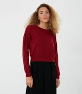 Buzo de punto color bordó, con cuello redondo, manga larga y sisa desplazada.