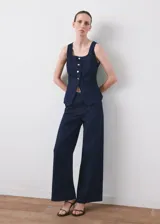 Top de denim color azul oscuro, con escote cuadrado, sin mangas y cierre frontal con botones.