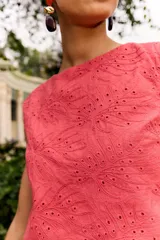 Top corto sin mangas color rosa fresa, con cuello redondo y diseño bordado con perforaciones en toda la prenda.