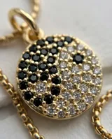 Collar de bronce dorado con cadena fina y dije circular con diseño de Yin Yang pavimentado con circones negros y blancos.