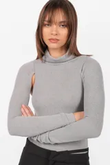 Body gris de tejido de punto con cuello alto y mangas largas. Presenta aberturas en los hombros, broches snap en la entrepierna y elástico interno en el contorno de tiro.