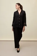 Camisa blanca de calce relajado, con cuello clásico, mangas 3/4 y cierre frontal de botones. Presenta bordados florales en relieve y detalles de crochet calado en los puños y el ruedo.