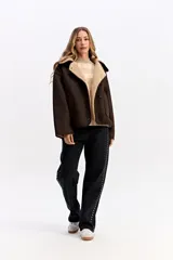 Campera de estilo aviador en color marrón oscuro, con exterior efecto gamuza e interior de corderito sintético color beige. Presenta cuello amplio, cierre frontal con botones y bolsillos laterales.