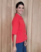 Cardigan de punto color arena, con cuello camisero, cierre frontal de botones y mangas cortas con terminación acanalada. Presenta dos bolsillos frontales tipo parche.