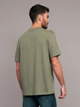 Remera de algodón de corte regular, color verde militar, con cuello redondo y estampado frontal con el logo de Calvin Klein dentro de un recuadro brillante.