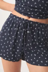 Pijama corto de color azul marino con pequeño estampado floral blanco, compuesto por una musculosa con detalles de encaje en el escote y un short con cordón ajustable en la cintura.