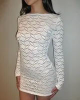 Minivestido tejido calado color blanco, de corte ajustado y mangas largas.