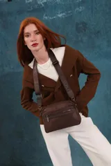 Bandolera de diseño moderno y funcional, confeccionada en nylon color marrón claro. Cuenta con múltiples compartimentos con cierre metálico, herrajes plateados y una correa ancha ajustable con detalle de marca.