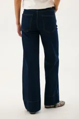 Pantalón de jean azul oscuro, de corte acampanado, con bolsillos delanteros y traseros, y costuras verticales en el frente.