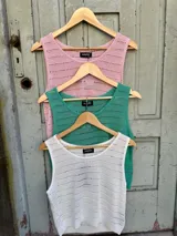 Blusa sin mangas de tejido de punto calado, color rosado, con cuello redondo.