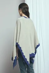 Poncho marrón con detalles de bordes ondulados en color rosado, confeccionado en mezcla de acrílico, poliéster y elastano, de diseño abierto y mangas amplias.