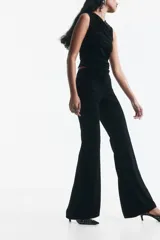 Pantalón negro de tiro alto con cierre y corchete oculto, modelo ajustado con bolsillos insertados atrás y piernas acampanadas.