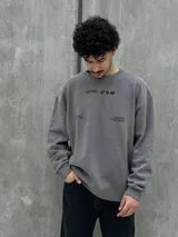 Buzo gris con cuello redondo, mangas largas y puños y bajo acanalados. Estampado frontal con el logo "Osten" y la frase "A mindset of becoming".