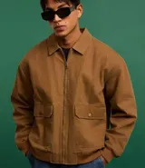 Campera bomber marrón de sarga de algodón, con cuello inglés, cierre frontal con cremallera, bolsillos cargo con botón y puños y cintura ajustados.
