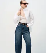 Pantalón de jean con corte new carrot, de cintura alta y estructura firme. Presenta un diseño holgado en la cadera que se estrecha hacia el bajo, con bolsillos funcionales y cierre frontal con botón y cremallera.