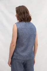 Chaleco azul de lino con cuello mao, abotonado al frente y bolsillos ojal con ribete blanco.