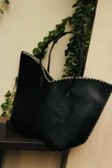 Cartera de cuero color marrón chocolate con manijas largas y borde superior en corte en V. Diseño amplio y liviano, con terminaciones artesanales y costuras contrastantes en todo el contorno.