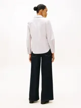 Camisa de popelina de algodón elástico a rayas verticales finas en tonos blanco y rosa. Tiene cuello inglés, puños y bajo camisero. Presenta logo de Tommy Hilfiger bordado en el pecho.