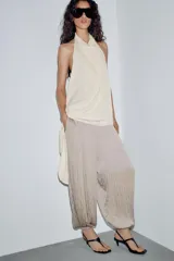 Pantalón de tiro medio con cintura elástica y bajo acabado en puño elástico. Presenta un diseño con tejido efecto arrugado y bolsillos laterales ocultos en costura.