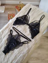 Conjunto de lencería de encaje negro compuesto por un bralette con detalle de aro central y una tanga de doble tira regulable estilo less.
